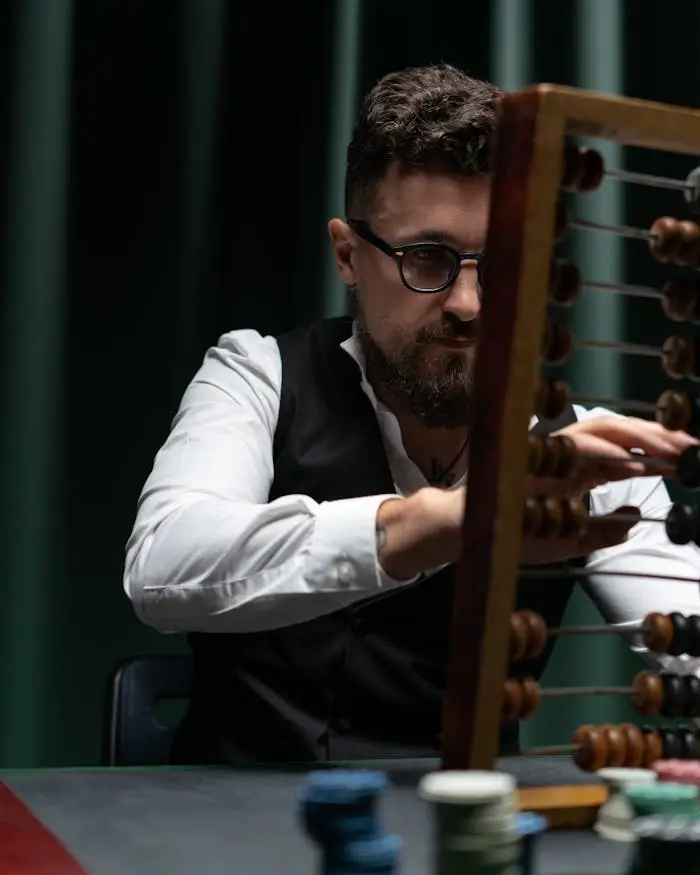 Businessman uses abacus with poker chips, capturing vintage calculation and gambling ambiance.