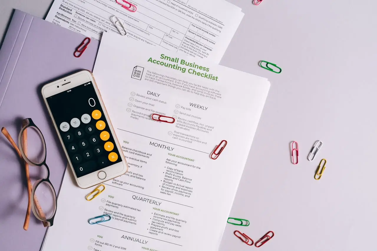 Top view of accounting essentials including smartphone, eyeglasses, and paperwork.